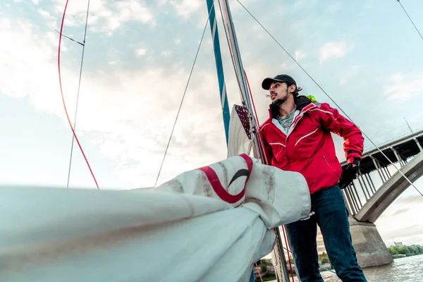 Yacht sailor pulling rope. Man working on sailboat.