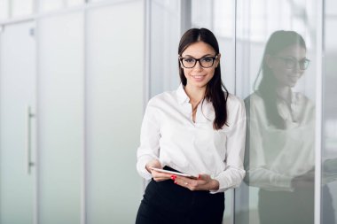 Young business woman with tablet computer opening glass office door