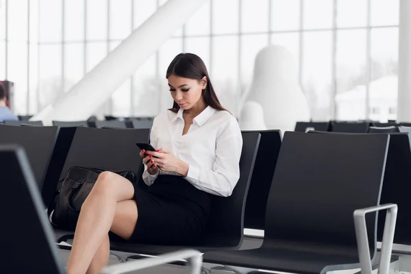 Mujer de negocios en su teléfono inteligente esperando en el aeropuerto —  Fotos de Stock