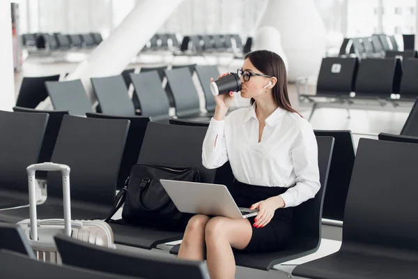 Молодая предпринимательница в аэропорту, используя ноутбук и питьевой кофе, путешествия, деловая поездка и активный образ жизни — стоковое фото