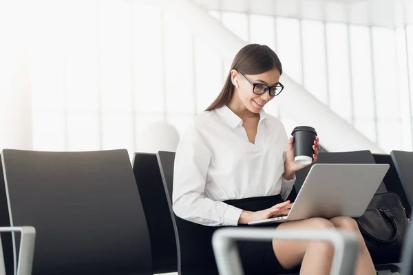 Mulher gosta de laptop e bebe café no terminal do aeroporto — Fotografia de Stock