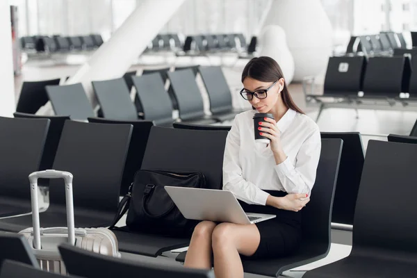 Casual γυναίκα που εργάζεται σε φορητό υπολογιστή στην αίθουσα αεροδρομίου. Γυναίκα περιμένει τη πτήση του αεροδρομίου στον τερματικό αεροσταθμό, κάθεται σε καρέκλα και πληκτρολογώντας στο φορητό υπολογιστή. — Φωτογραφία Αρχείου