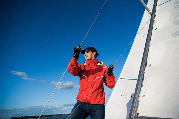 Vista a basso angolo di marinaio che opera verricello su yacht. Lavorare con corde e vela — Foto Stock