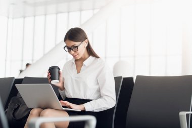 Bir Havaalanı Kalkış salonda otururken dizüstü bilgisayarda çalışan genç kadın