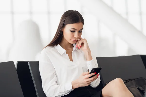 Τηλέφωνο γυναίκα διαβάζει μηνύματα στο αεροδρόμιο αίθουσα αναμονής. Ευτυχισμένο κορίτσι αγοράζοντας ηλεκτρονικό εισιτήριο, κάνοντας κρατήσεις ξενοδοχείων και check in σε απευθείας σύνδεση. — Φωτογραφία Αρχείου