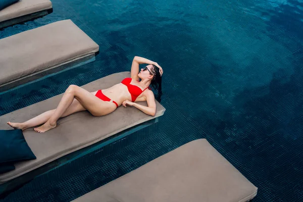 Mujer acostada en una tumbona junto a la piscina en el hotel . — Foto de Stock