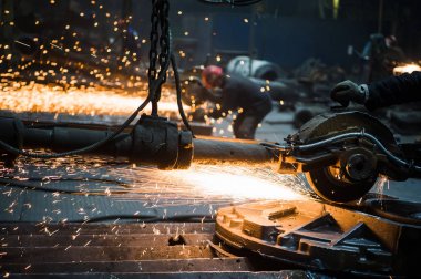Erkek işçi ellerinin yakın çekim, özel koruyucu eldiven giyen, büyük elektrikli öğütücü ile metal kesme, fabrikada çelik ile çalışırken uçan turuncu kıvılcım. Tehlikeli iş kavramı.