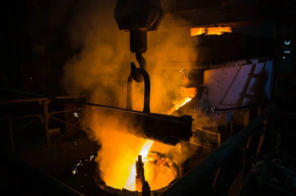 Molten steel pouring. Liquid hot metal of steel spills out of the ladle at steel factory.