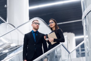 Genç işadamları bir merdiven üzerinde duran ve modern ofis binasında konuşurken.