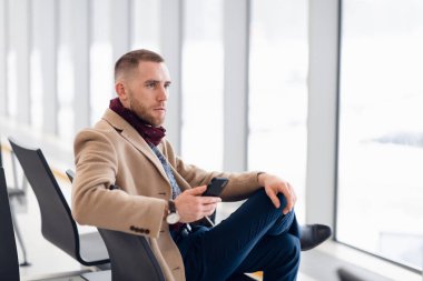 onun telefonu kullanırken kalkış Havaalanı'nda bekleyen genç meşgul adam