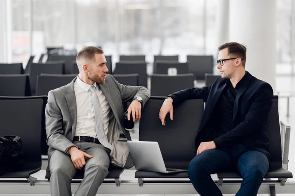 Compañeros de negocios esperando en el salón del aeropuerto sentado y hablando —  Fotos de Stock