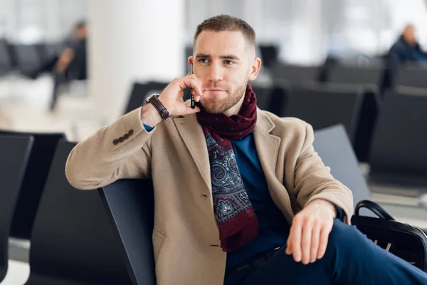 Молодий серйозний чоловік в шарфі і пальто говорить на мобільному телефоні крупним планом . — стокове фото