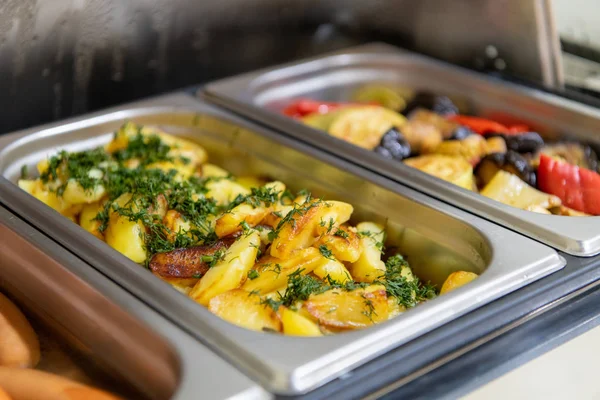 Cuñas de patata, salchichas y verduras a la parrilla en marmita en el desayuno del hotel —  Fotos de Stock