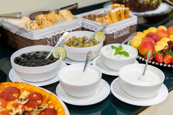 Una selección de salsas, aceitunas, cuajada y guarniciones en el mostrador buffet de un restaurante —  Fotos de Stock