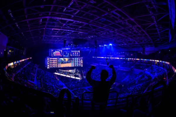 MOSCÚ, RUSIA - 14 DE SEPTIEMBRE DE 2019: evento de videojuegos de esports. Feliz aficionado dedicado a los deportes electrónicos animando a su equipo favorito en una tribuna frente a una gran pantalla con las manos levantadas . —  Fotos de Stock