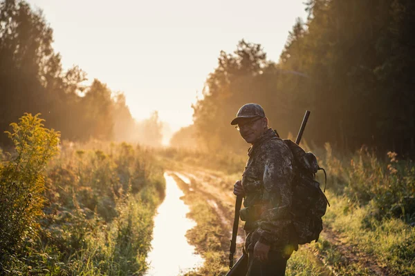 Madárvadász a Sunrise-nál vadászni megy az erdőben a puskájával.. — Stock Fotó