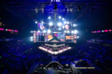 Esport etkinliğinin arka planında bulanıklık var. Büyük bir stadyumdaki bilgisayar oyunları turnuvasının büyük bir sahnesi aydınlandı. Tribünler video oyunu hayranlarıyla dolu..