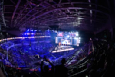 Esport etkinliğinin arka planında bulanıklık var. Büyük bir stadyumdaki bilgisayar oyunları turnuvasının büyük bir sahnesi aydınlandı. Tribünler video oyunu hayranlarıyla dolu..