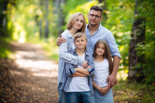 Portrait of happy family of four in a green summer park — Stock Photo, Image