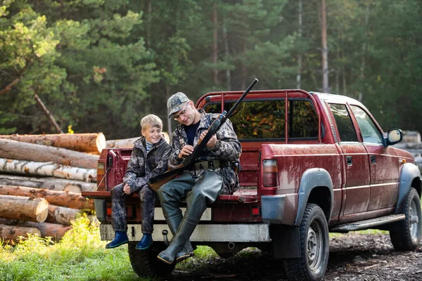 Человек в грузовике с сыном в лесу. Хантер учит мальчика стрелять из дробовика. . — стоковое фото