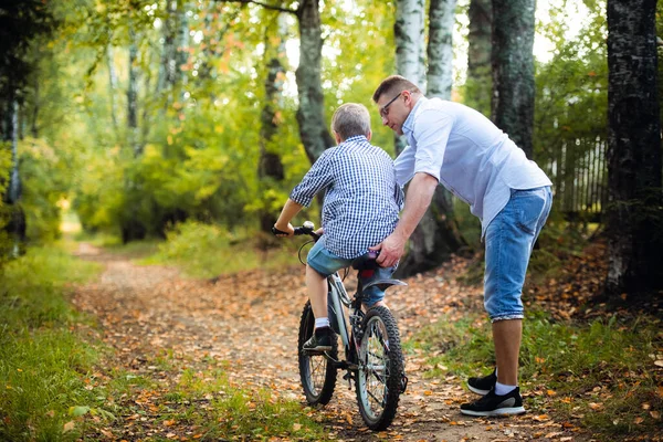 Jeune père enseignant à son fils à faire du vélo — Photo