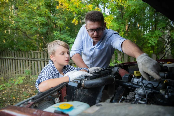 Padre enseñando a su hijo cómo comprobar el aceite en el coche familiar . — Foto de Stock