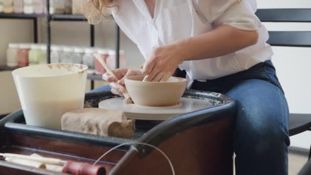 Potter rende il prodotto argilloso con strumenti di modellazione della ceramica sulla ruota vasai. — Video Stock