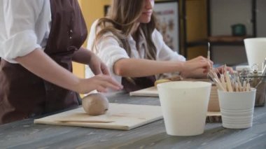 Kadın çömlekçi masadaki kil parçasını şekillendiriyor. Kadın seramik bir şey yapıyor. Sanat stüdyosunda çömlekçilik, el yapımı ve yaratıcı beceriler..