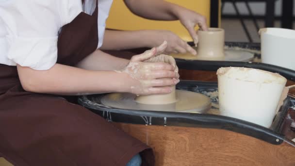 Två kvinnor gör keramik på en keramik hjul, forma lera med händerna, närbild. Keramik hantverk verkstad på konst studio. — Stockvideo