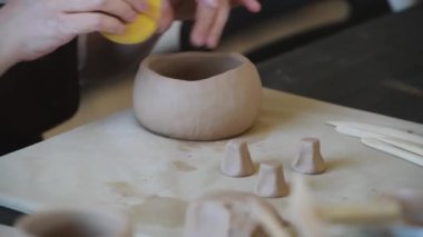 Stüdyoda, çömlek atölyesinde süngerli profesyonel kadın çömlekçi şekillendirme ve oyma kupası. El işi, sanat eseri ve el yapımı konsept..