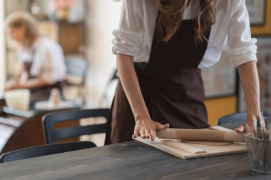 Kadın eli, seramik stüdyodaki ahşap merdaneyle kumaş parçalarını düzleştiriyor..