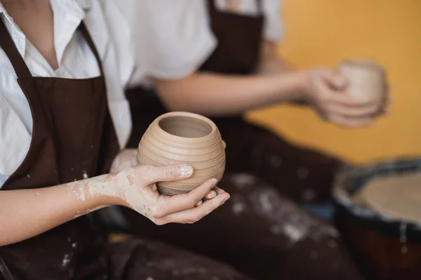 女陶工做完了一个陶瓷瓶,把它从陶瓷轮上取出来.用白土做花瓶.用白土制作陶瓷制品，特写 — 图库照片