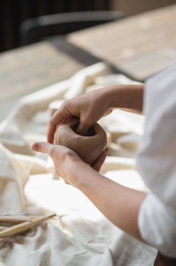 Kadın çömlekçi masadaki kil parçasını şekillendiriyor. Kadın seramik bir şey yapıyor. Sanat stüdyosunda çömlekçilik, el yapımı ve yaratıcı beceriler..