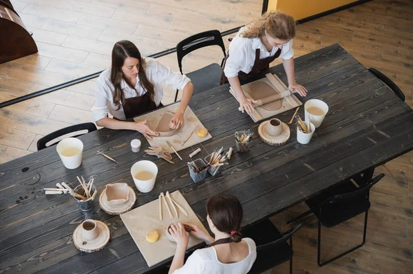 在现代艺术工作室里，年轻美丽的女艺术家正在手工制作陶器。教育儿童和家长. — 图库照片