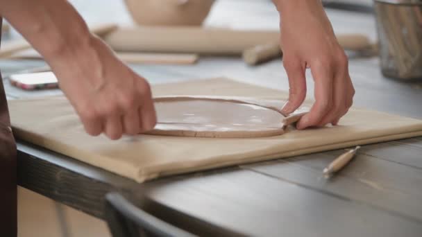 Крупный план квалифицированной ремесленницы удаление части глины при изготовлении керамической продукции в керамической мастерской — стоковое видео