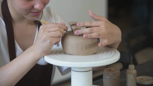 Zamknij żeńskie dłonie trzymając kij i robiąc ozdoby na ceramice. Glinowy produkt do formowania glinki. Pojęcie sztuki ceramicznej i hobby. — Wideo stockowe