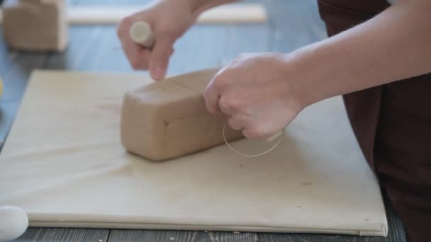 Подготовка белой глины к работе. Резка слоев глины для скульптуры в мастерской гончара крупным планом. Сырой кусок глины на старом деревянном столе в керамике. — стоковое видео