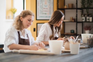 Çömlek atölyesinde çalışan, gülümseyen ve konuşan kadınlar. Seramik atölyesi, çömlek ustası sınıfı..