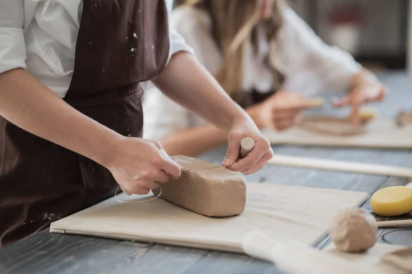女性の陶芸家は、トリミングツールのクローズアップを使用して陶器の粘土の作品を切断。女性は粘土カッターを粘土の生の部分に使用する — ストック写真