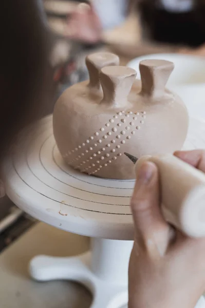 Closeup de fundo de caneca, que está sendo decorado em estúdio de cerâmica. Mãos profissionais femininas fazendo pontos de argila ou gotas na superfície do vaso por ferramenta de compressão especial. — Fotografia de Stock