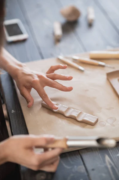 Gros plan de l'artisan qualifié enlever une partie de l'argile tout en faisant des produits céramiques dans l'atelier de poterie — Photo