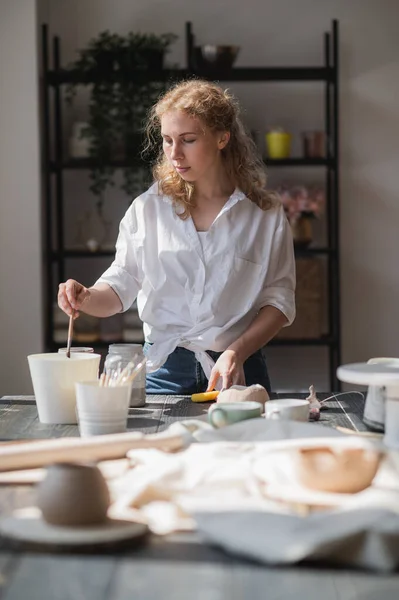 Γυναίκα αγγειοπλάστρια φτιάχνει κεραμικά πιάτα στο στούντιό της. Διαδικασία εργασίας κεραμικού δοχείου υαλοπινάκων. — Φωτογραφία Αρχείου
