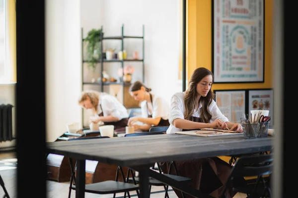 Mooie jonge vrouwelijke kunstenaar meisjes maken handgemaakt aardewerk in moderne kunst studio. Onderwijs kinderen en ouders. — Stockfoto