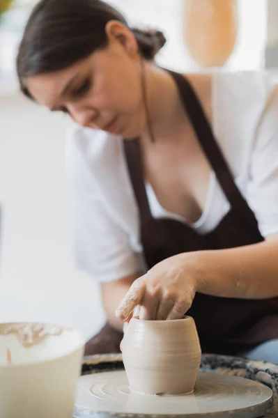 Gros plan du potier qui fabrique du pot dans un atelier de poterie. Utilisation de l'éponge et de l'eau pour hydrater l'argile. — Photo