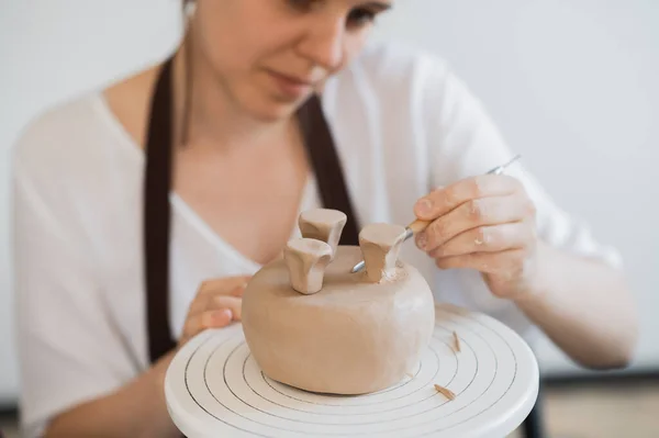 スティックを保持し、装飾品に飾りを作る女性の手。陶磁器工房の土師型粘土. — ストック写真