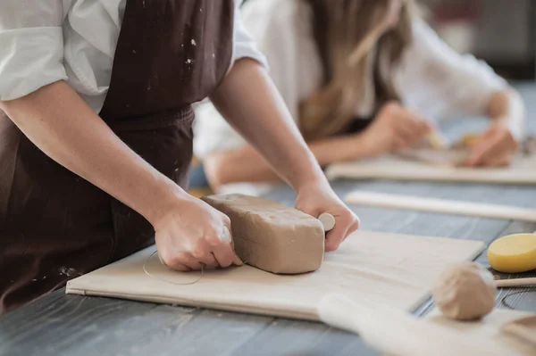 Жіночий гончар формує шматок глини за столом. Жінка робить керамічний предмет. Керамічні роботи, майстерність ручної роботи та творчі здібності в художній студії . — стокове фото