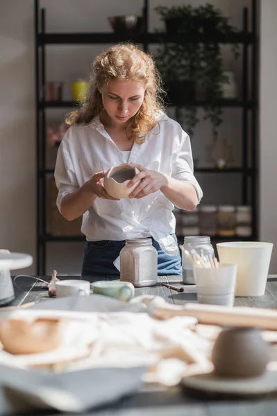 Femme potier vitrage brut tasse en céramique non brûlée à l'aide d'un pinceau. Tasse en terre cuite mettant colorant sur atelier de poterie. — Photo