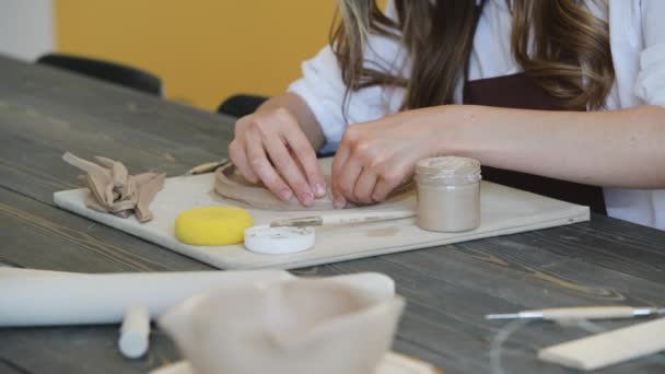 Konstnärlig kvinnlig krukmakare förbereder material för sin keramik. Kvinnliga händer fästa lera del till framtida keramiska produkt. Arbete på nära håll. — Stockvideo
