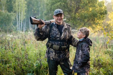 Güler yüzlü avcı ya da silahlı asker yaz ormanlarında kuş avı sırasında yanında çırağı vardı..