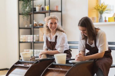 Potter 'ın ellerini, çömlekçilik atölyesinde hareket eden çömlekçi çarkında su kullanarak işlenmemiş toprak kilini şekillendirirken kapat..